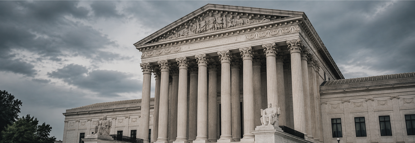 The U.S. Supreme Court building photographed from below against a dramatic overcast sky, with tall marble columns and classical architecture visible in the foreground.